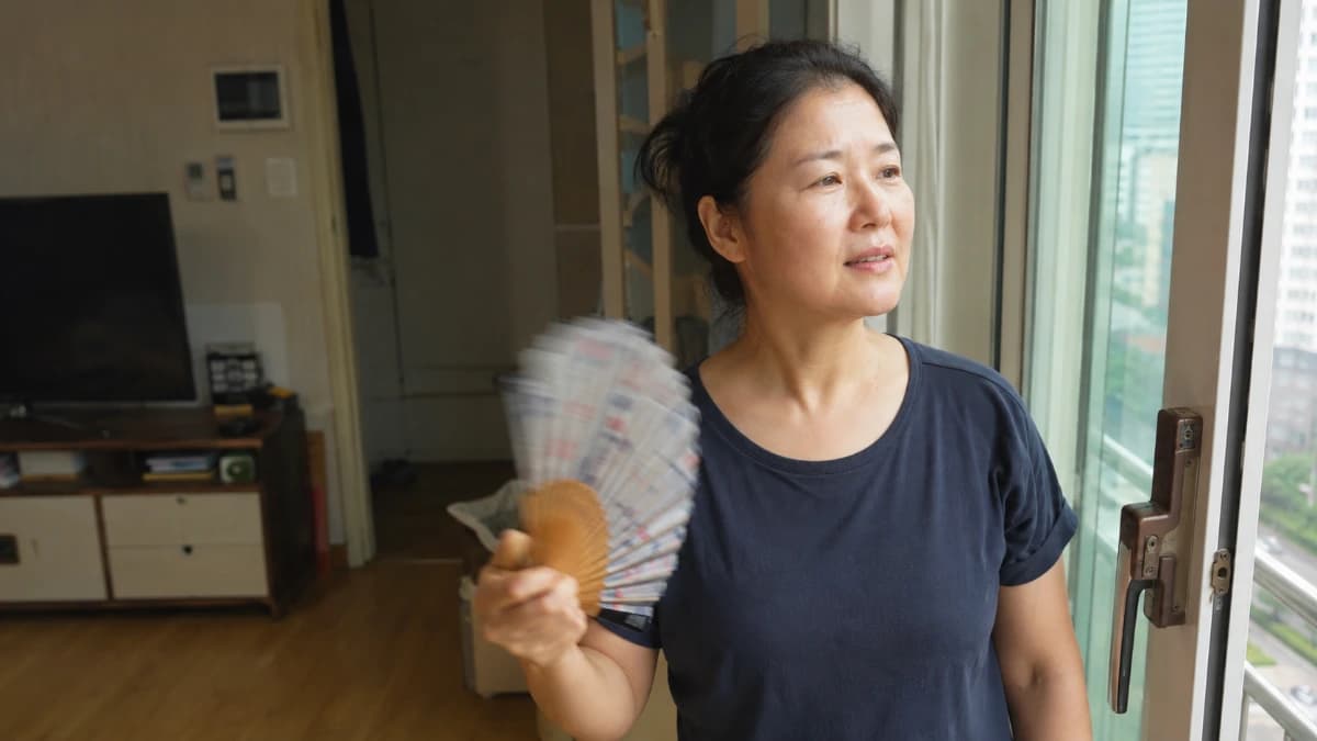 창가에서 부채질을 하는 40대 후반 한국 여성