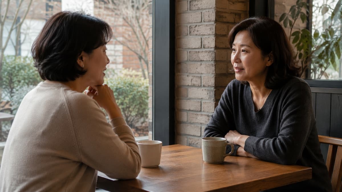 낮의 동네 카페 창가에서 마주 앉아 이야기를 나누는 두 사람