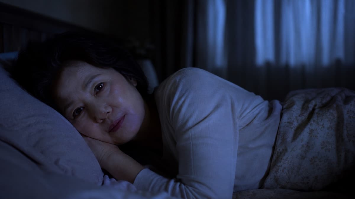 밤에 잠들지 못하고 베개에 머리를 둔 채 눈을 뜨고 있는 여성